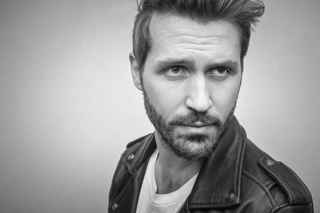 Close-up black and white portrait of a man in a leather jacket with a serious expression.